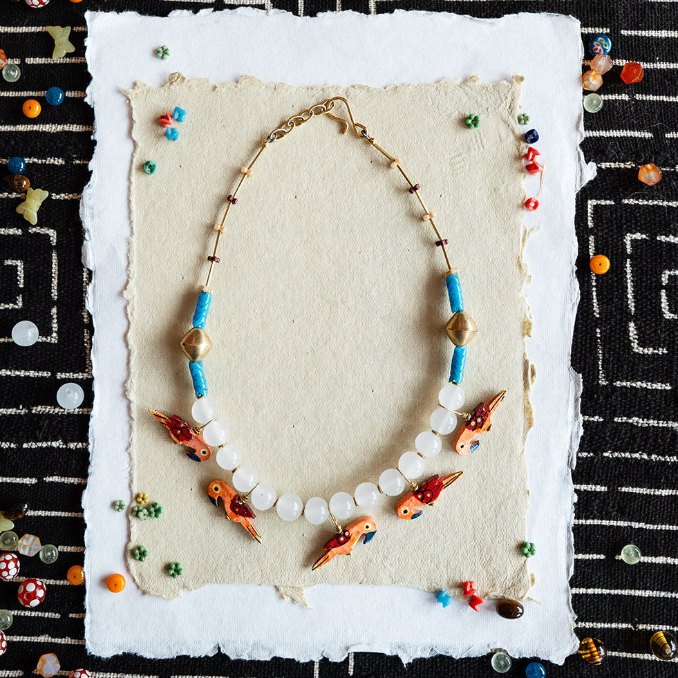 Necklace with colorful beads on a textured card against a black and white patterned background