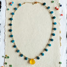 Necklace with colorful beads on a white card against a black patterned background