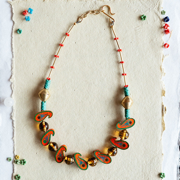 Necklace with colorful beads on a textured card against a black and white patterned background