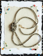Three beaded necklaces on a textured white card with a black and white geometric patterned background.