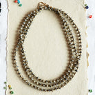 Necklace displayed on a white card with colorful beads on a black textured background