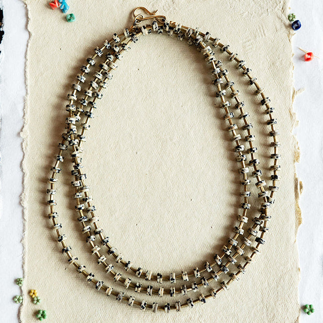 Necklace displayed on a white card with colorful beads on a black textured background