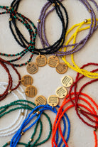 Colorful beaded bracelets with gold charms on a light background