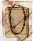 Gold chain necklace on a textured surface with a white background