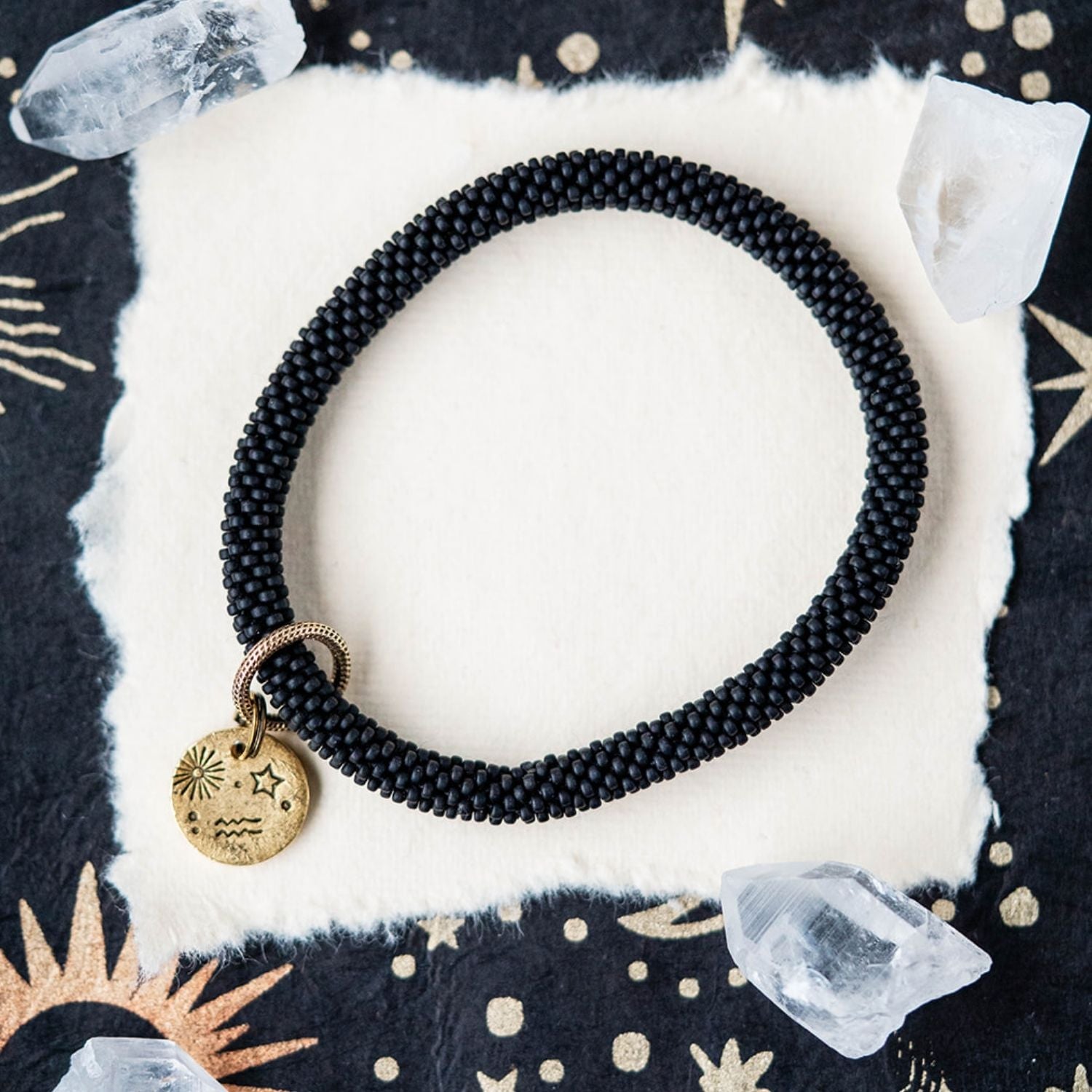 Black beaded bracelet with gold Aquarius zodiac charm styled with clear crystals and celestial elements