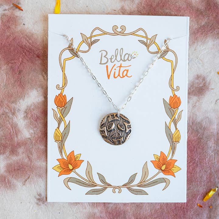 Close-up of Bella Vita Art Nouveau bronze flower necklace on an elegant floral-themed card. Perfect handcrafted jewelry gift.