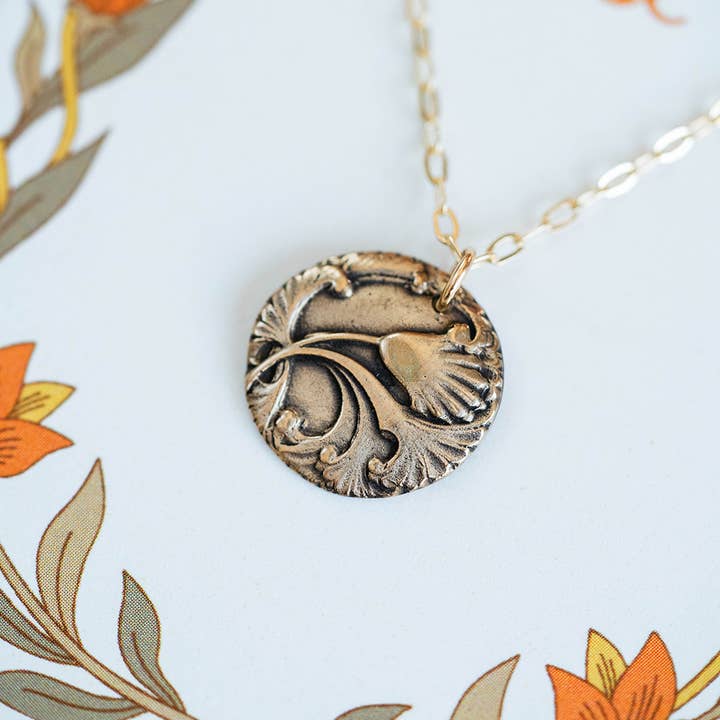 Close-up view of the Art Nouveau Single Flower Necklace bronze pendant with intricate floral detailing.