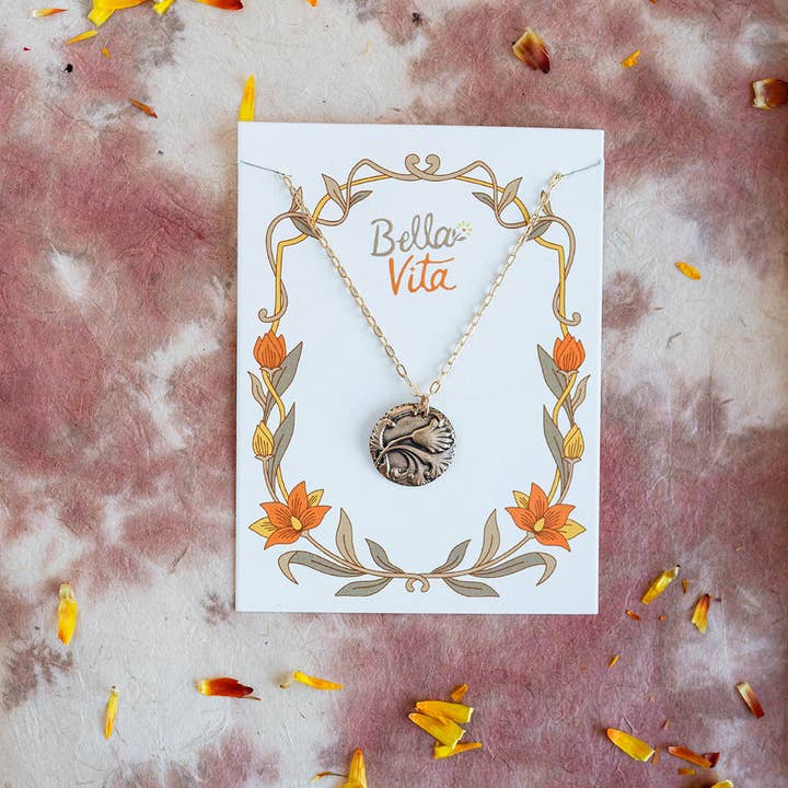 Flatlay of the Art Nouveau Single Flower Necklace surrounded by petals and decorative items, emphasizing its vintage appeal.