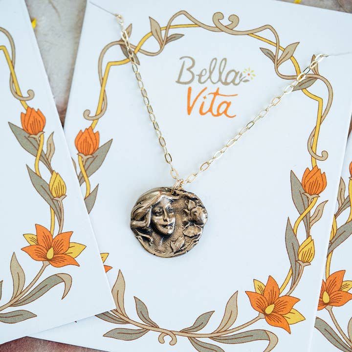 Close-up view of the Art Nouveau Double Flower Necklace displayed on a Bella Vita necklace card, showcasing intricate bronze pendant details.