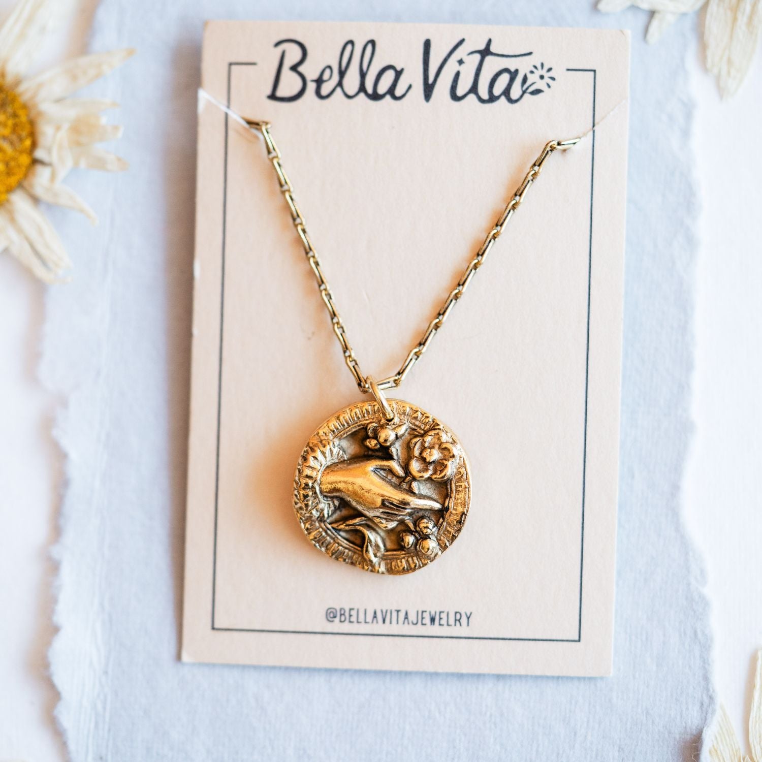 Gold cast bouquet heirloom pendant shown with Bella Vita artisan jewelry packaging and daisies