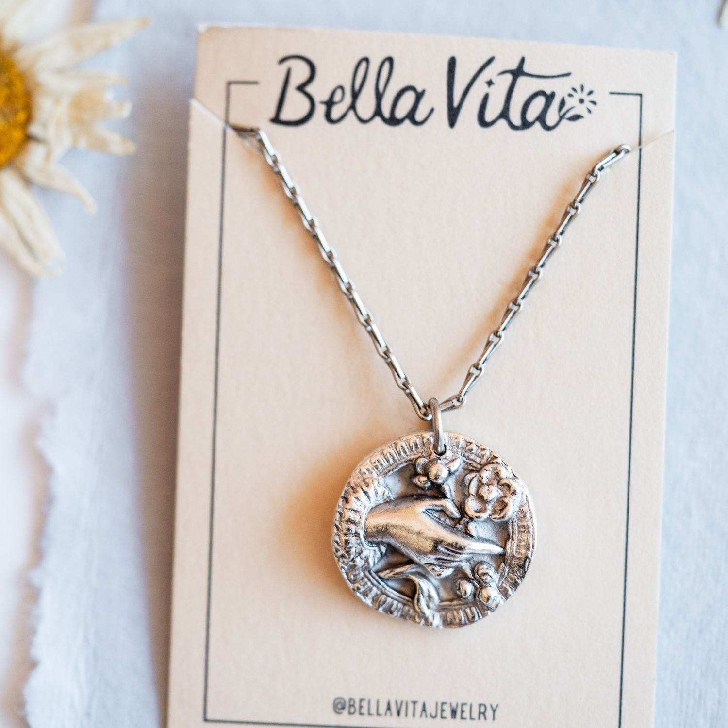 Silver cast bouquet heirloom pendant displayed on Bella Vita branded card with daisy flowers