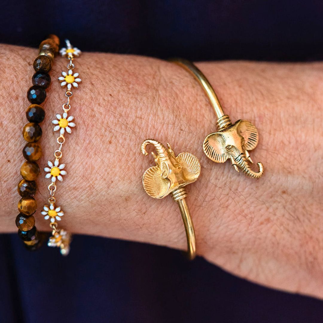 Handcrafted bracelet stack featuring gold elephant cuff bracelet paired with tiger's eye beads and delicate daisy chain bracelet by Bella Vita Jewelry"