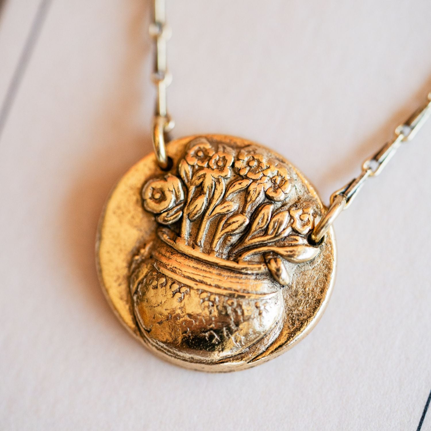 Artisan gold flower pot pendant necklace featuring vintage gardening button casting