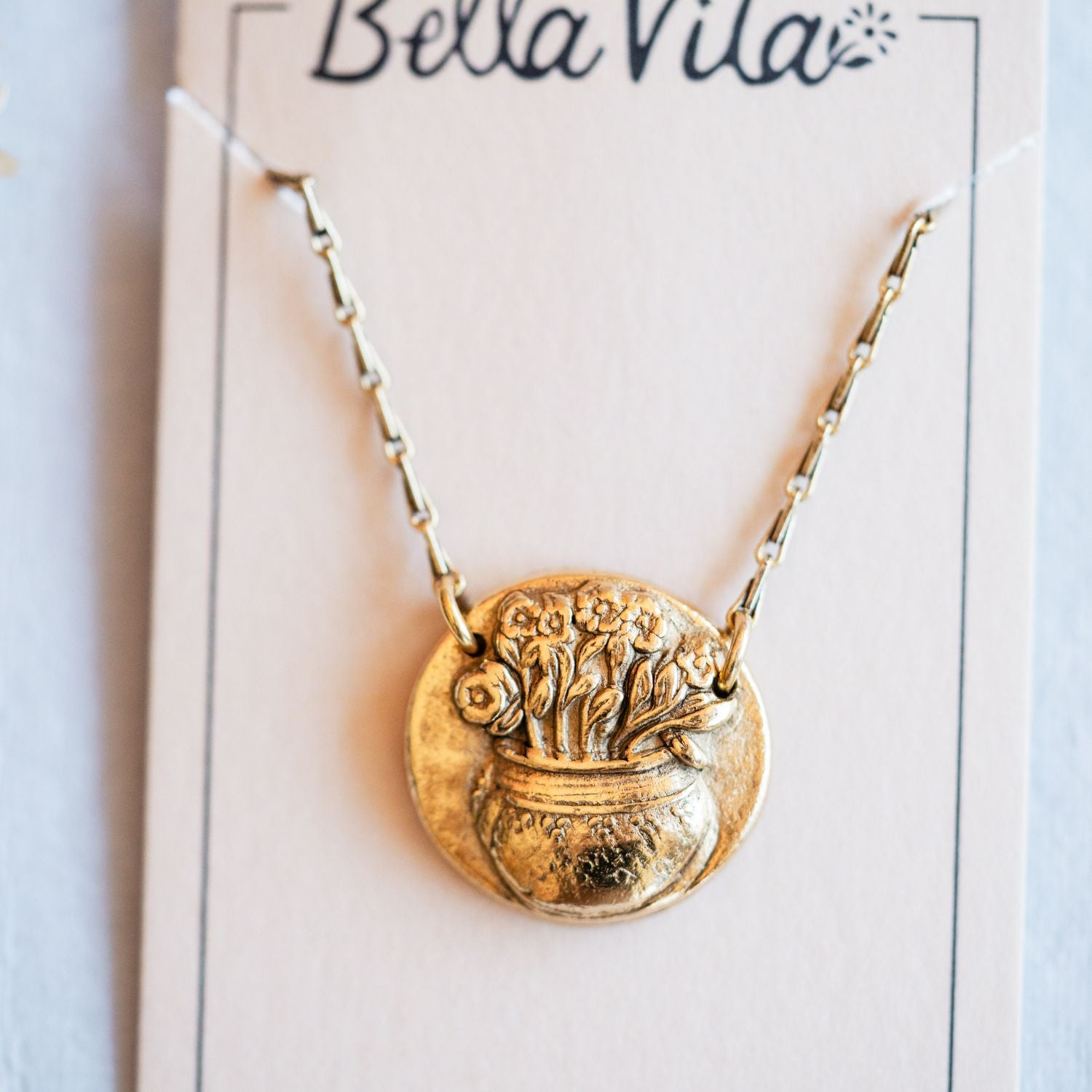 Gold cast flower pot heirloom pendant displayed on Bella Vita branded artisan jewelry card