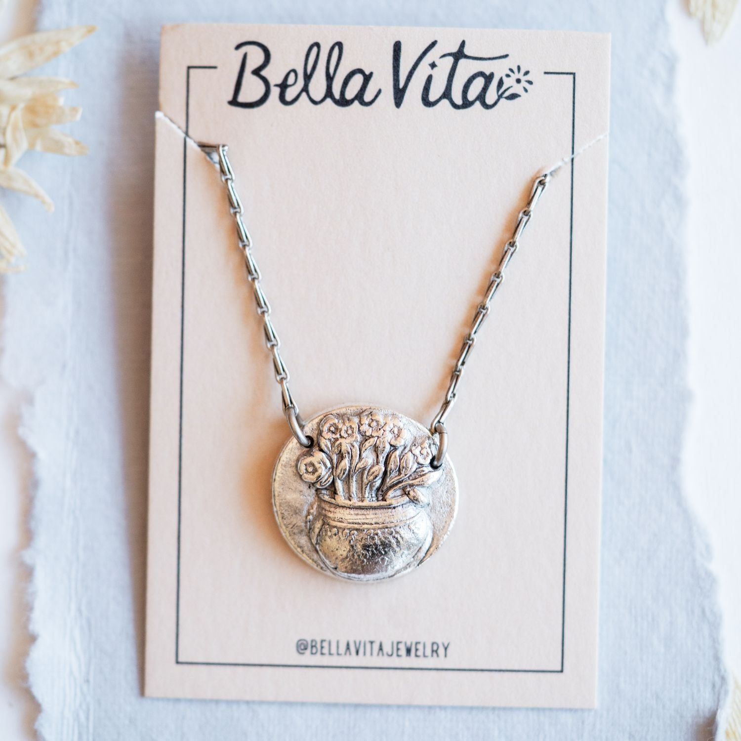 Silver cast flower pot heirloom pendant shown with Bella Vita artisan jewelry packaging