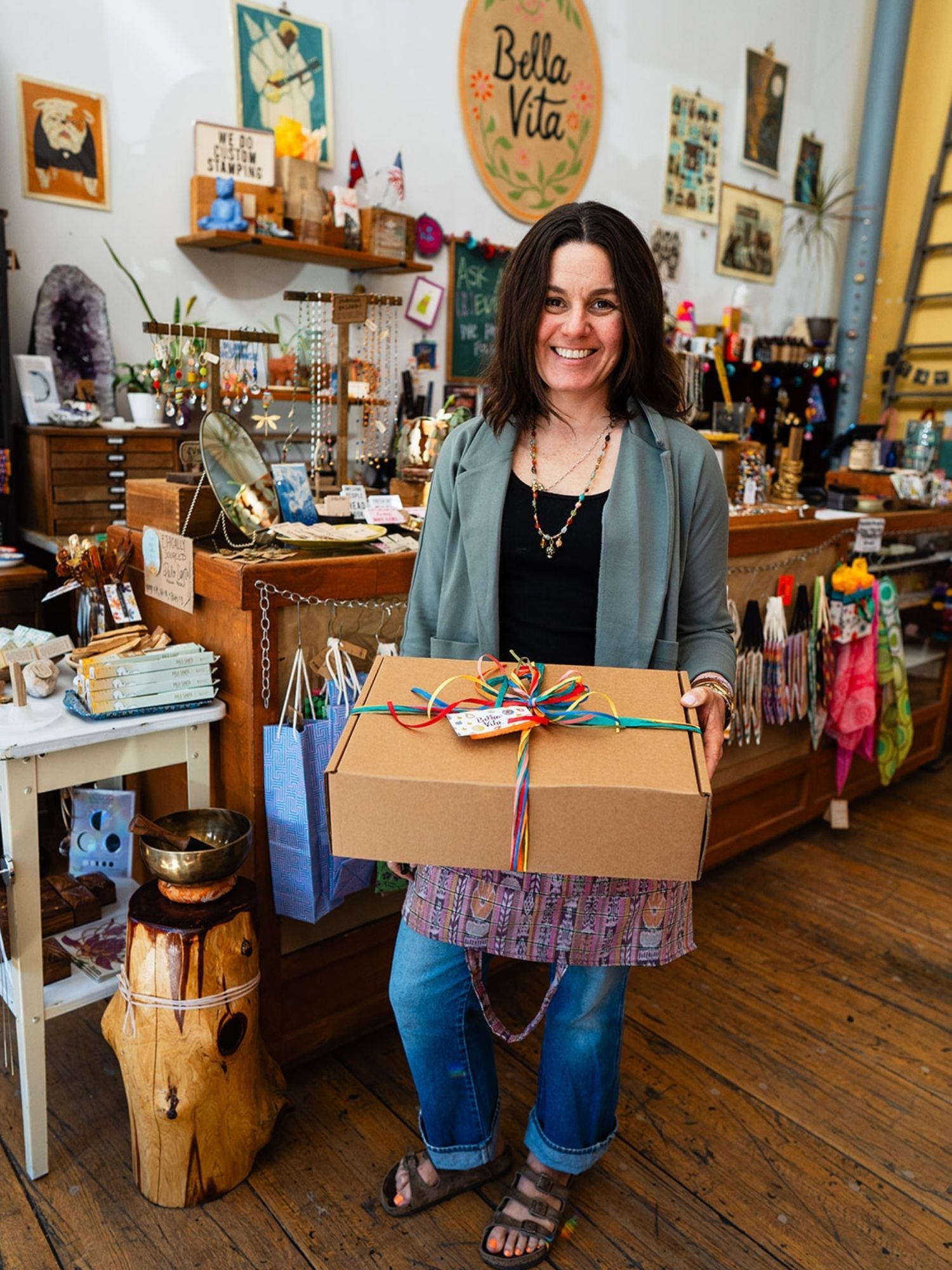 Bella Vita Jewelry owner holding a beautifully wrapped custom gift box with colorful ribbons inside the artisan jewelry store in downtown Little Rock.