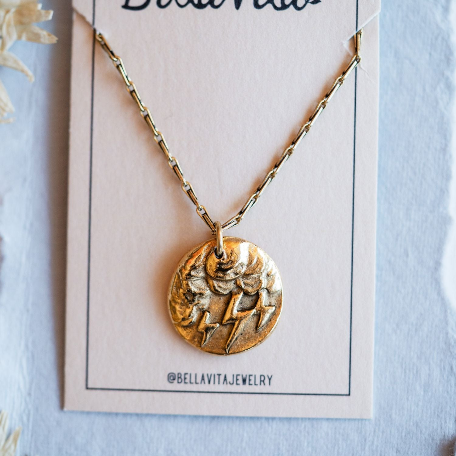Gold cast storm cloud heirloom pendant displayed on Bella Vita branded artisan jewelry card