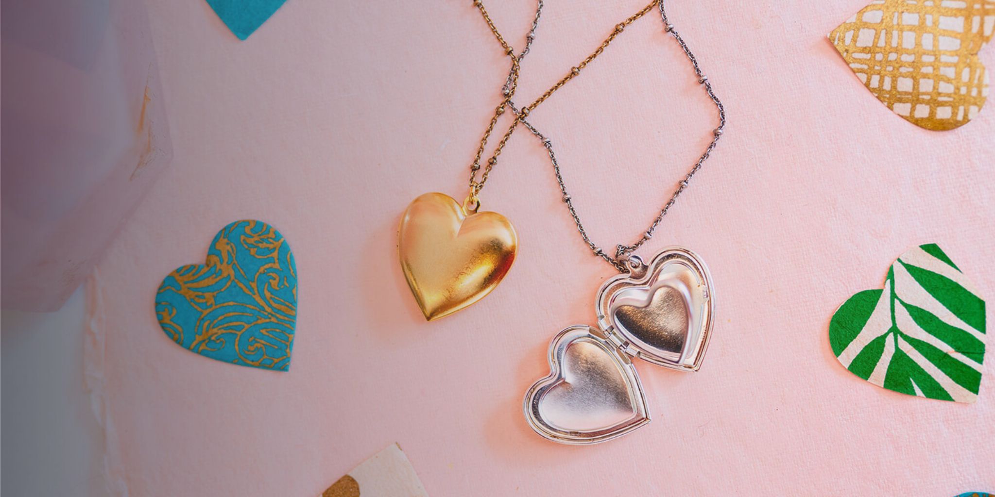 Bella Vita Valentine's Day heart locket collection featuring gold and silver designs with decorative heart pattern backdrop