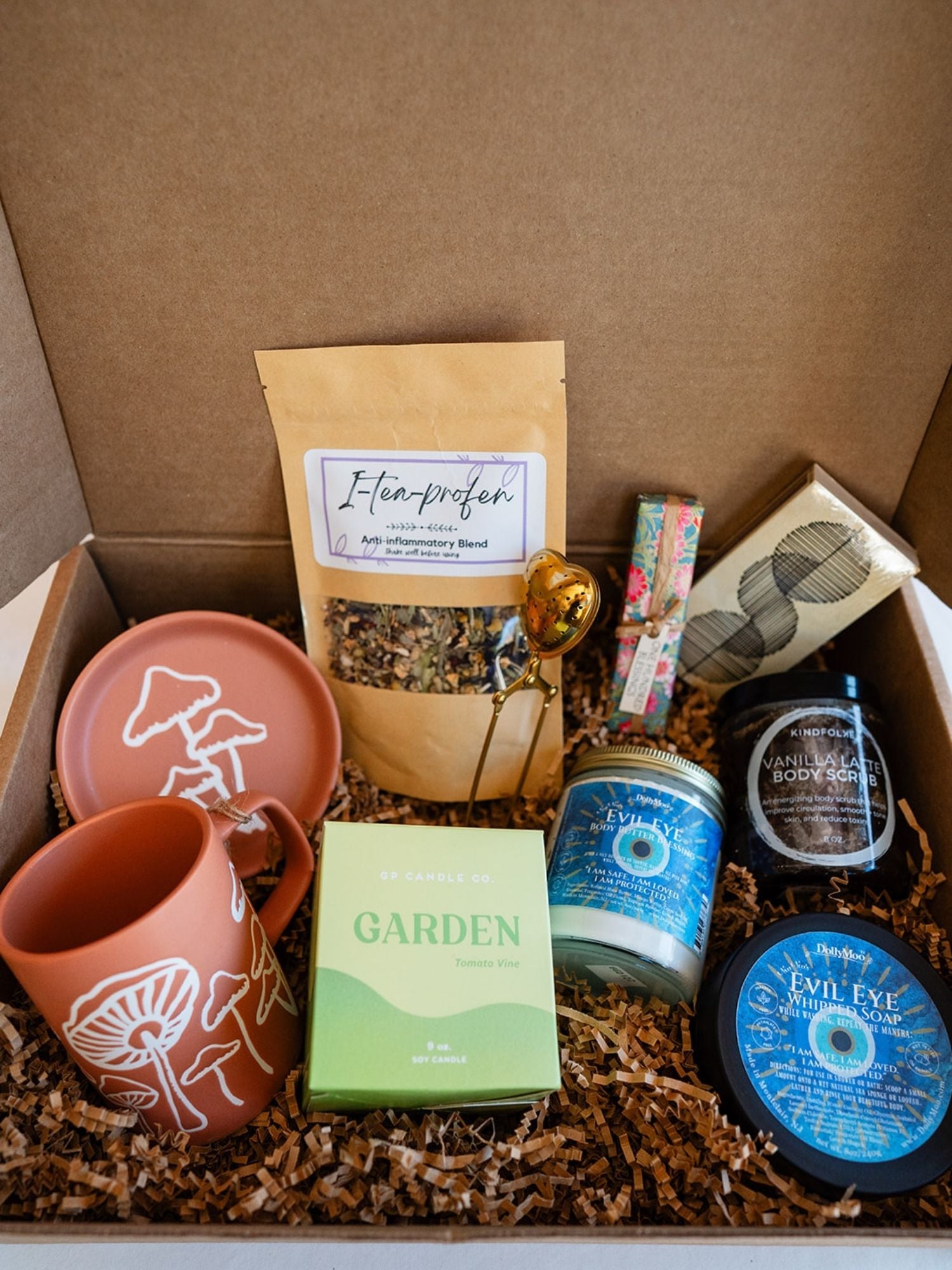Artisan wellness gift box from Bella Vita containing terracotta mushroom mugs, Evil Eye body products, I-tea-profen herbal blend, and a Garden candle.