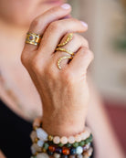 Hand modeling patterned brass serpent ring paired with colorful beaded bracele