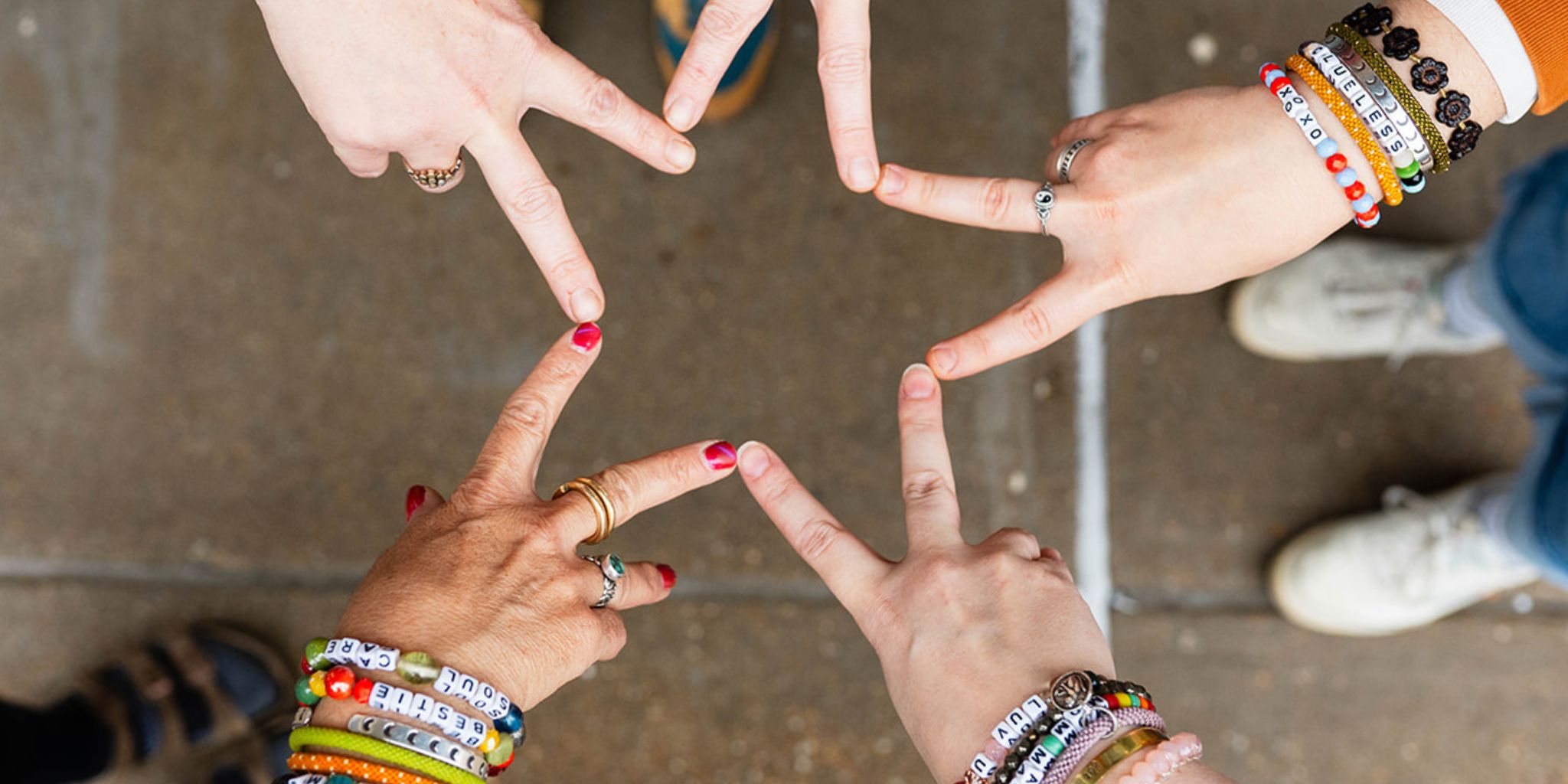 Hands wearing Bella Vita bracelets forming a star, celebrating community and creativity.