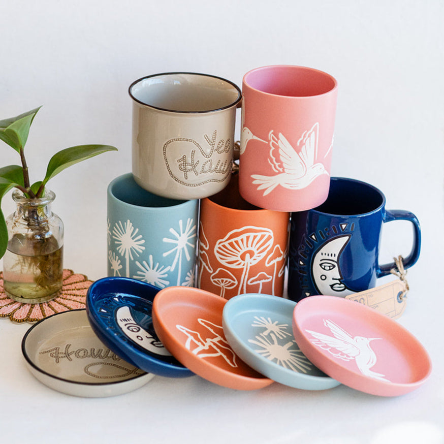Complete Cuppa Color ceramic collection showing all handcrafted mug and coaster sets in blue, pink, orange and cream with unique white silhouette designs.