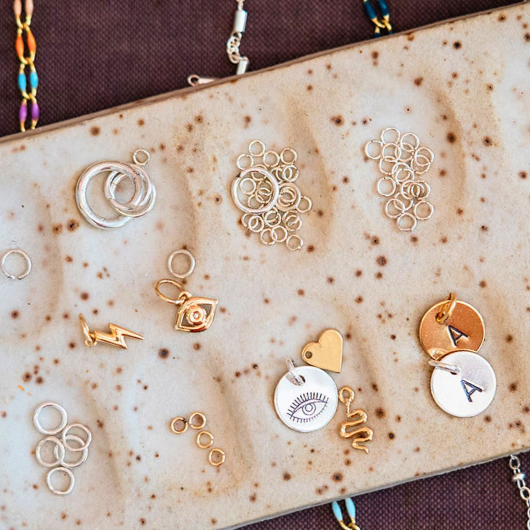 Permanent jewelry charm collection at Bella Vita downtown Little Rock - featuring personalized initials, protection symbols, and dainty design elements