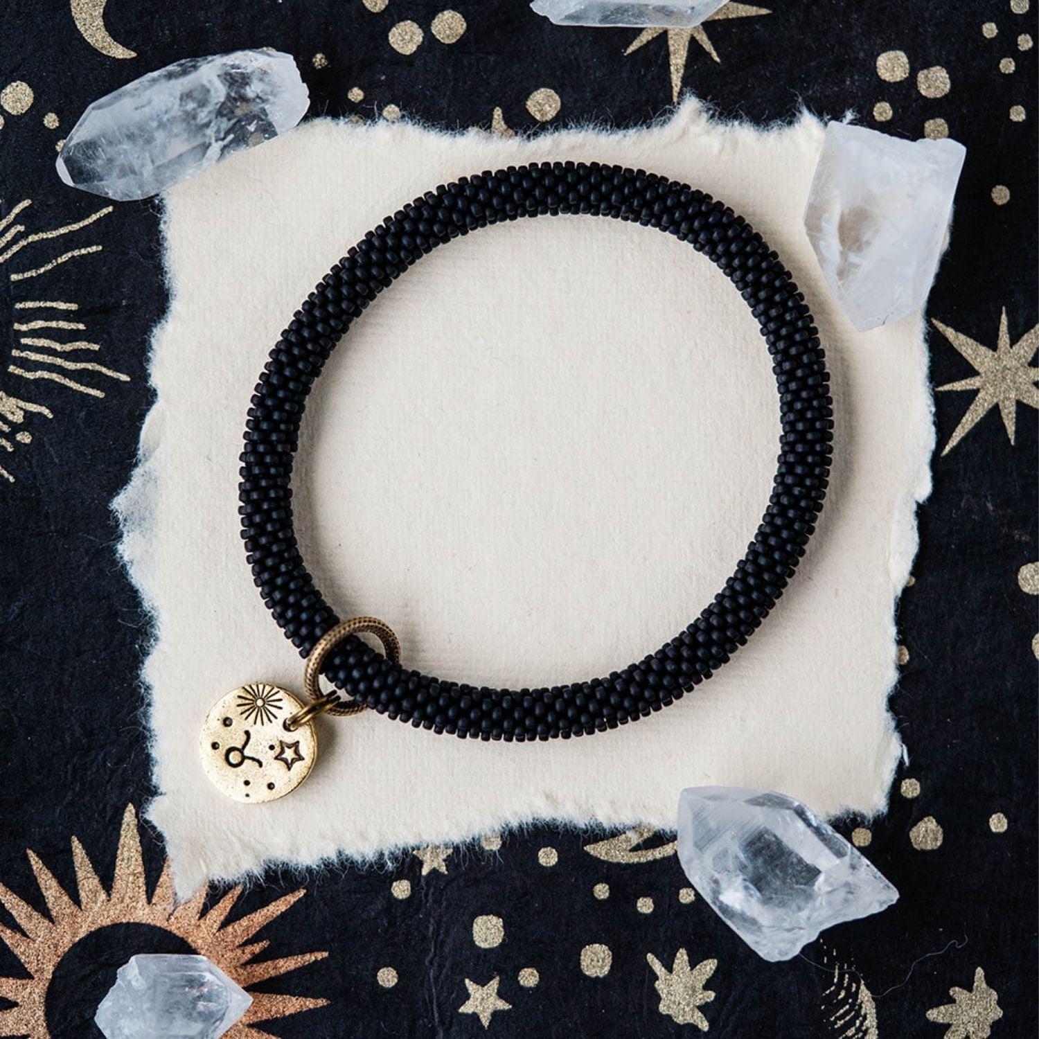 Black beaded bracelet with gold Taurus zodiac pendant styled with clear crystals and celestial elements