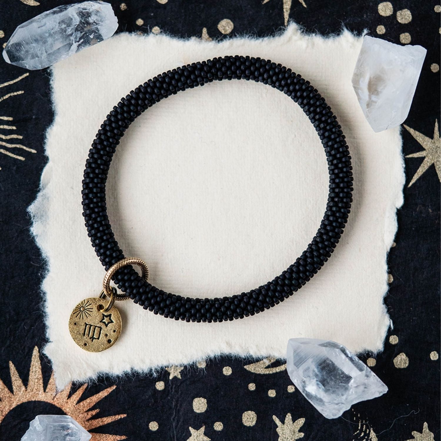 Black beaded bracelet with gold Virgo zodiac pendant styled with clear crystals and celestial elements