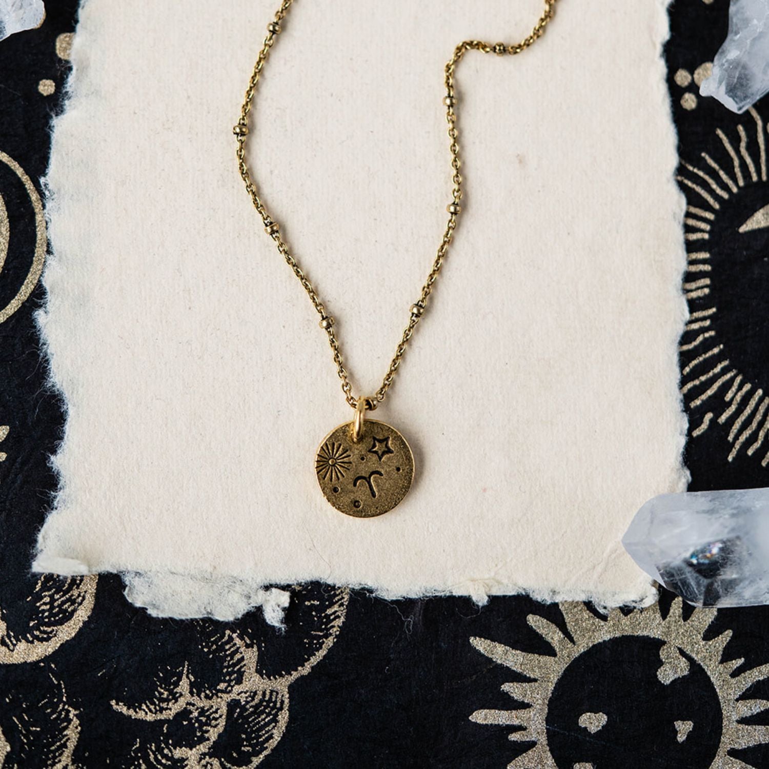 Aries constellation charm necklace with gold disc featuring engraved sun starburst and ram symbols