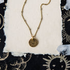 Aries constellation charm necklace with gold disc featuring engraved sun starburst and ram symbols