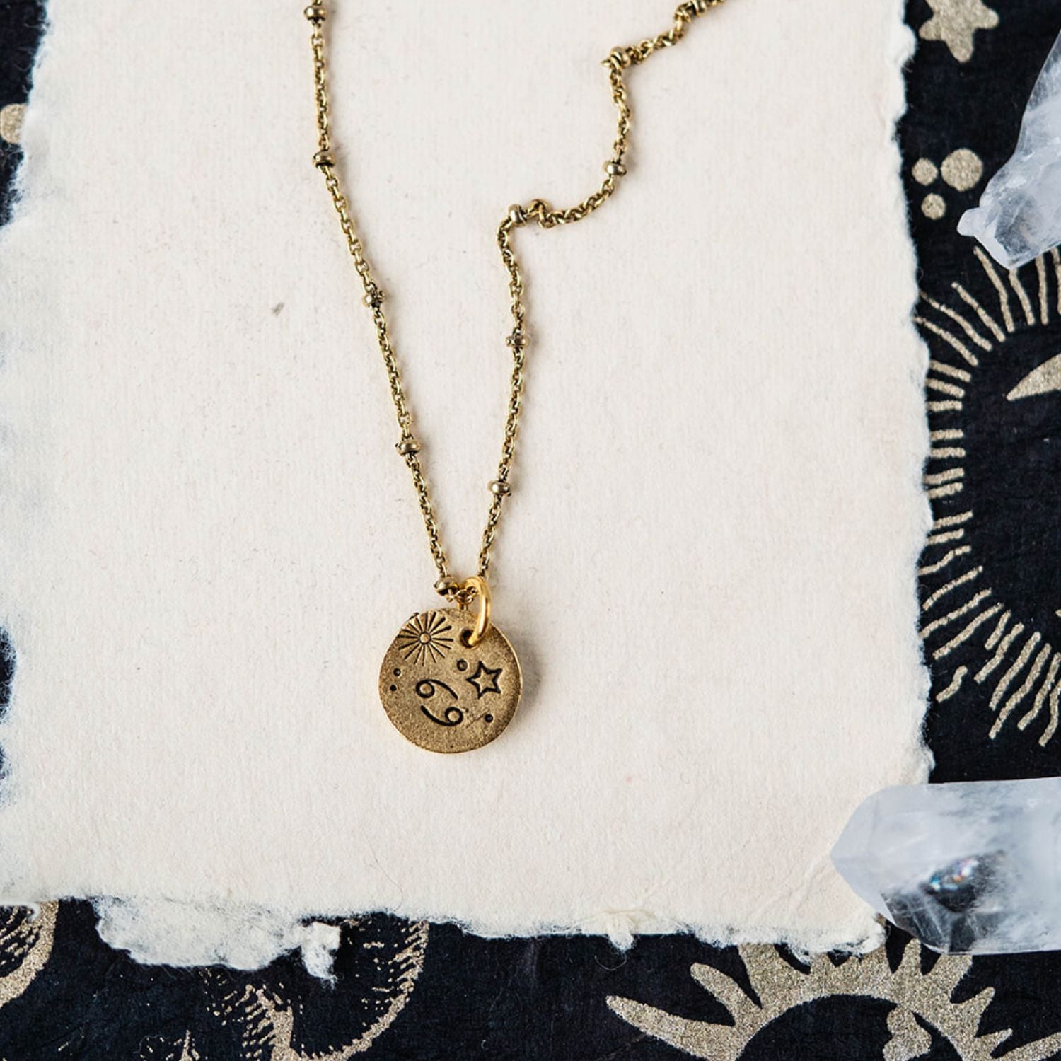 Cancer constellation charm necklace featuring gold disc with engraved crab and star motifs