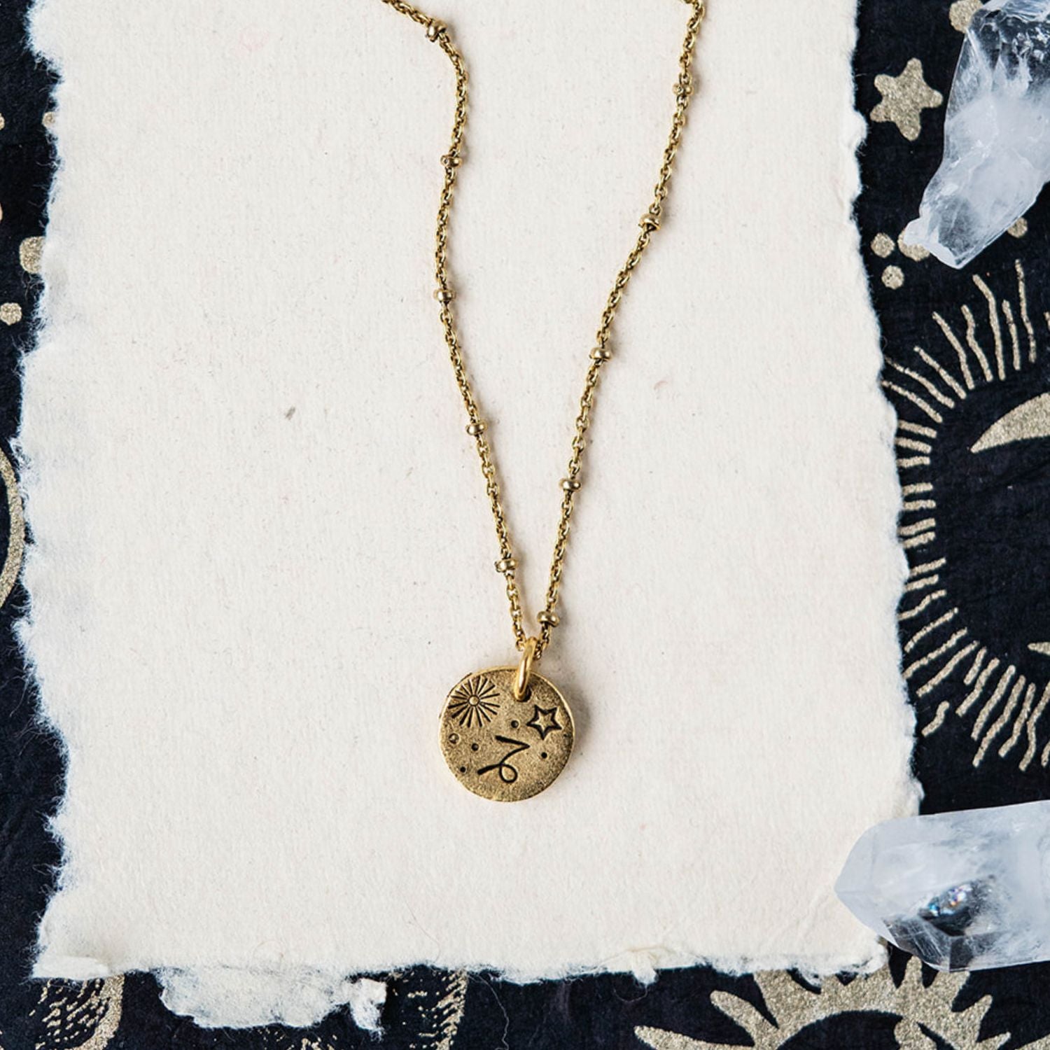 Gold Capricorn zodiac pendant necklace with goat horn symbols and celestial motifs on chain