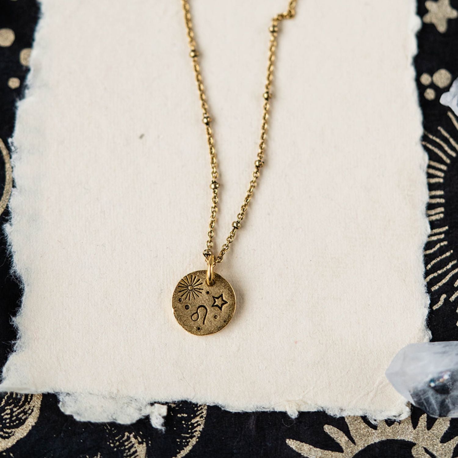 Leo constellation charm necklace featuring gold disc with engraved lion and star motifs