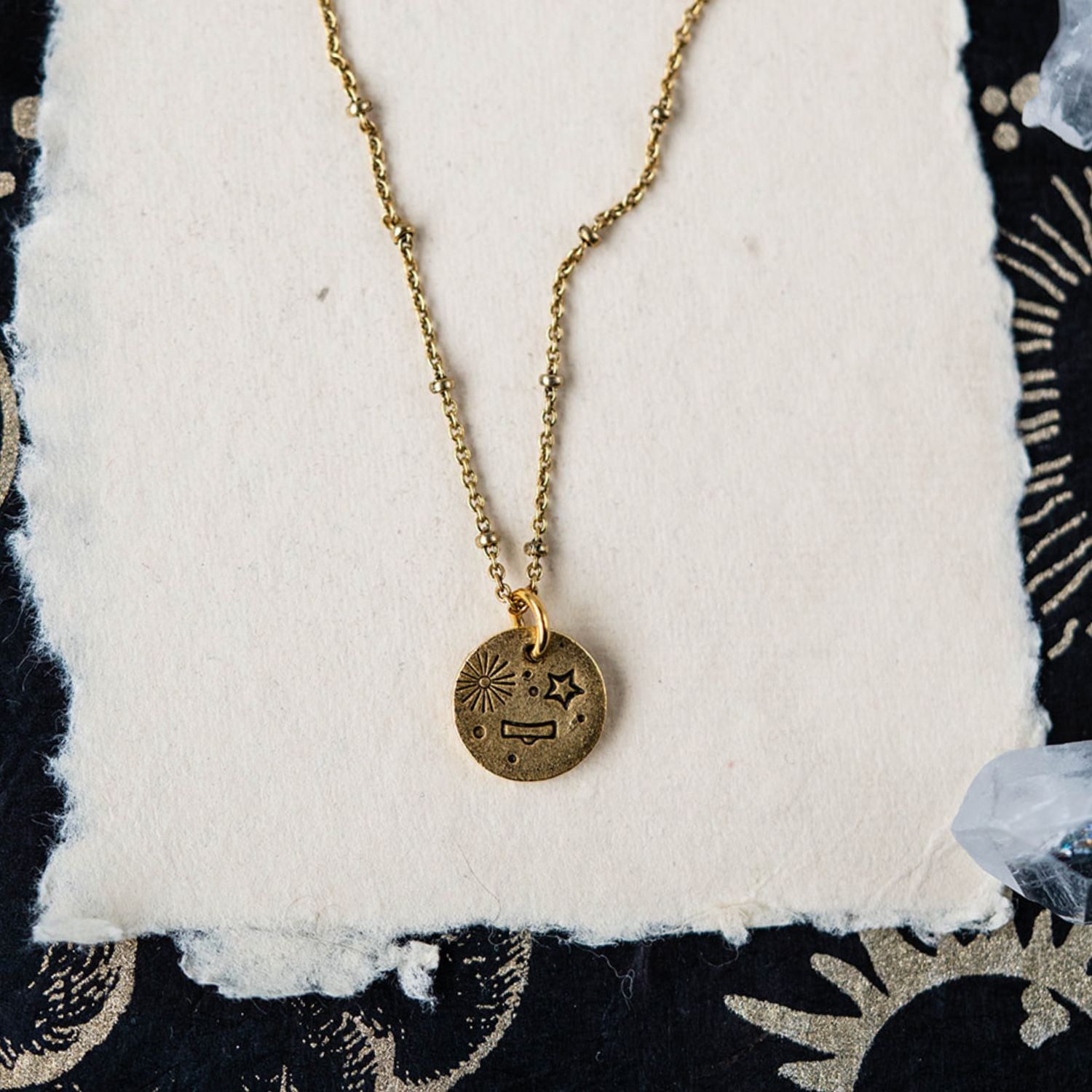 Libra constellation charm necklace featuring gold disc with engraved scales and star motifs