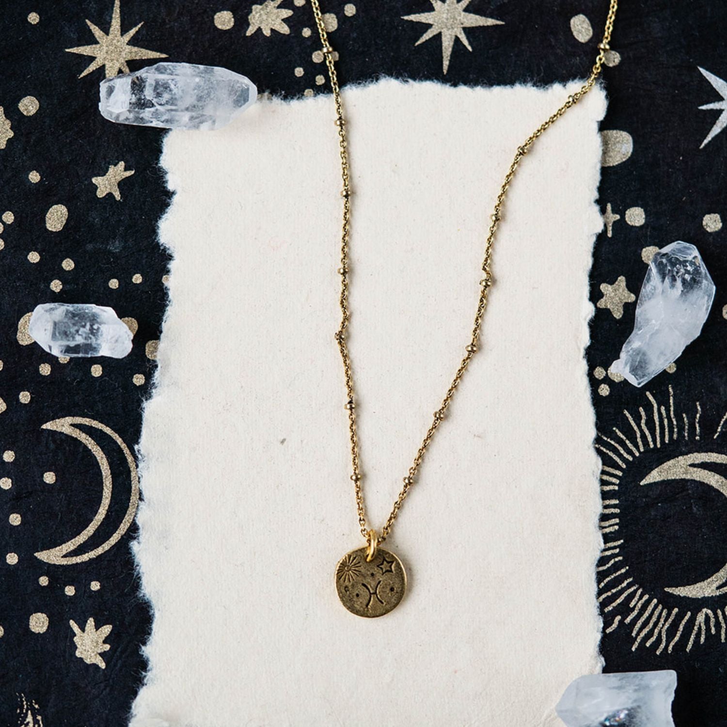 Pisces constellation charm necklace featuring gold disc with engraved fish and star motifs