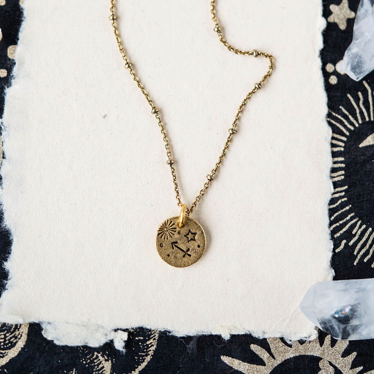 Sagittarius constellation charm necklace featuring gold disc with engraved archer and star motifs