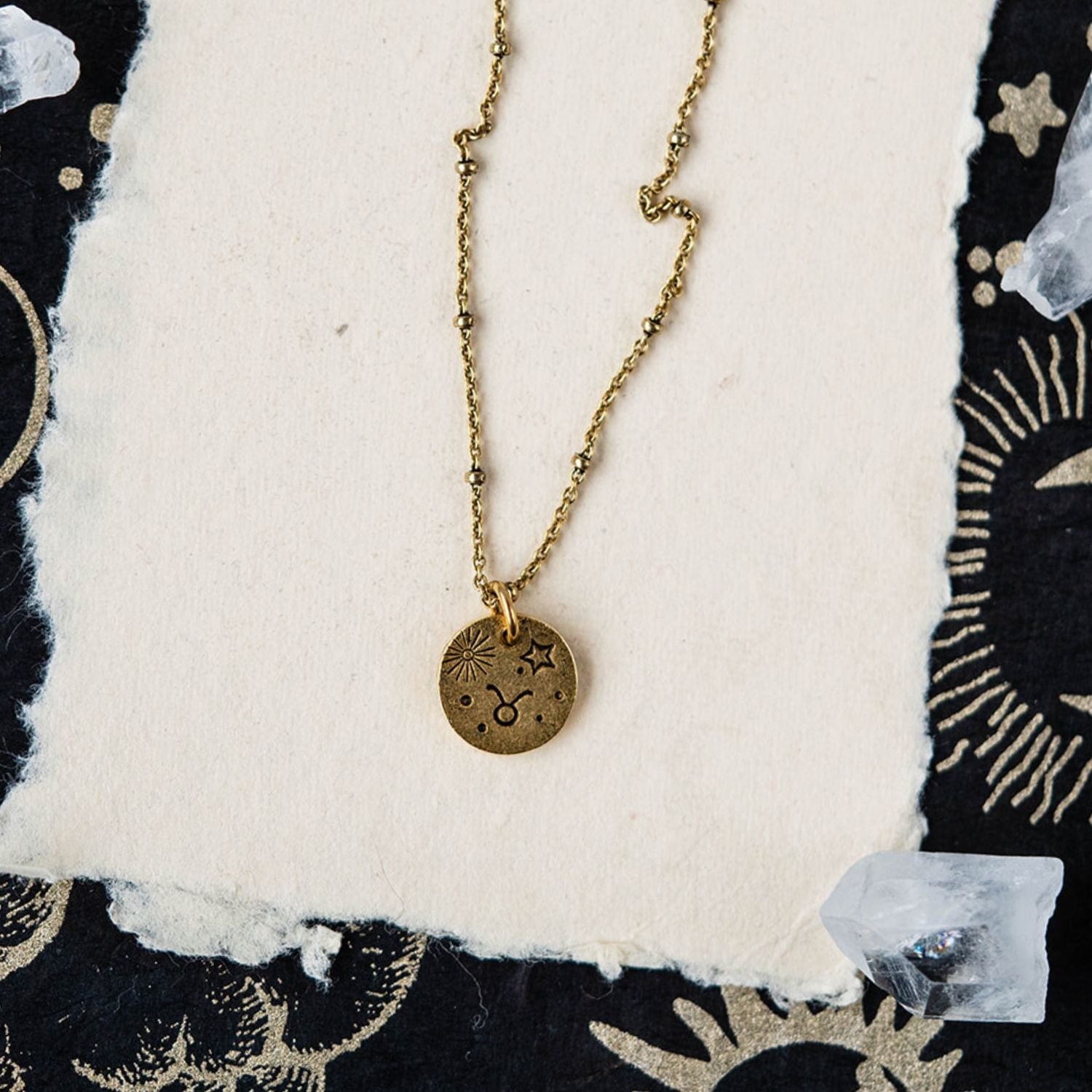 Taurus constellation charm necklace featuring gold disc with engraved bull and celestial symbols