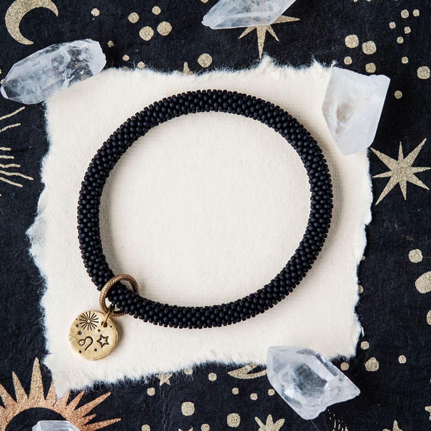 Black beaded bracelet with gold Leo zodiac pendant styled with clear crystals and celestial elements