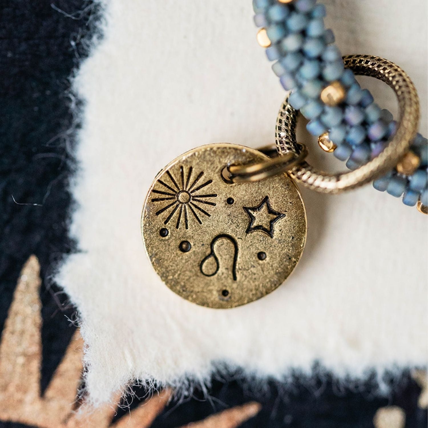 Gold Leo charm with blue-grey beaded jewelry showing lion constellation and sun engravings